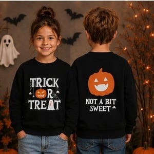 Könnte beinhalten: Zwei schwarze Langarm-Sweatshirts mit Halloween-Motiven. Das linke Sweatshirt zeigt den Schriftzug TRICK OR TREAT mit einem Kürbis und einem Geist. Das rechte Sweatshirt zeigt einen großen orangefarbenen Kürbis und den Text NOT A BIT SWEET.