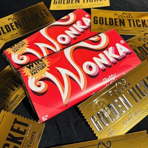 Peut inclure: Deux tablettes de chocolat Wonka rectangulaires dans des emballages rouge vif avec du texte stylisé blanc et orange, portant la mention Win A Trip To Wonka's Chocolate Factory, entourées de plusieurs cartes rectangulaires dorées Wonka Golden Ticket.