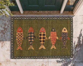 May include: A rectangular doormat with an olive green background and a dark border featuring a repeating geometric pattern. Five stylized fish are arranged horizontally across the center, each displaying unique patterns in shades of red, orange, and black.