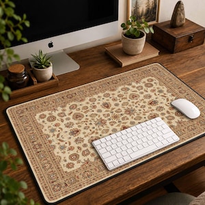 May include: A rectangular desk mat featuring a cream-colored base with an intricate, multi-colored floral and paisley pattern in shades of red, blue, and gold, finished with a decorative border and a black edge trim, placed on a wooden desk surface.