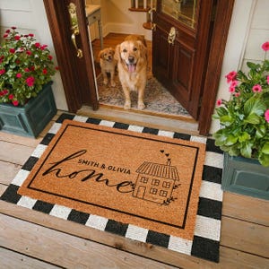 May include: A rectangular coir doormat with a black border, featuring the word home in script, the text SMITH & OLIVIA, and a line drawing of a house with three small hearts above it, layered over a black and white buffalo check rug.