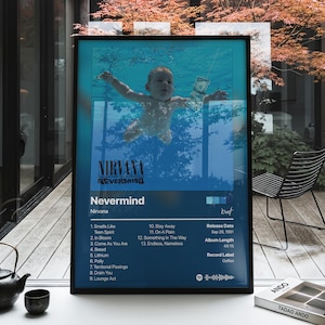 May include: A framed poster featuring the Nirvana Nevermind album cover art with a blue underwater scene of a baby, the band name, tracklist, release date of Sep 26, 1991, album length of 49:15, record label Geffen, and a Spotify code at the bottom.