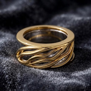 May include: A gold-toned ring featuring a wide band with an openwork design composed of multiple smooth, flowing, wave-like metal strands that wrap around the circumference, creating a layered and airy appearance with a polished, reflective finish.