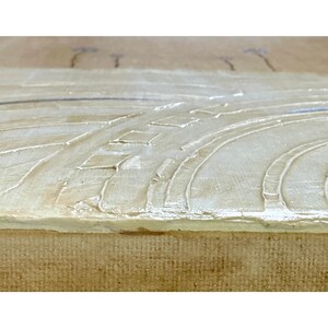 Op de afbeelding: Een getextureerd canvas schilderij met opgehoogde, gebroken witte impasto verf aangebracht in gebogen, lineaire patronen. Het oppervlak toont een dikke, gelaagde verfaanbreng met zichtbare penseelstreken op een neutrale, lichtbeige achtergrond.