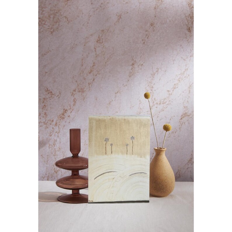 Op de afbeelding: Een rechthoekig schilderij op canvas met een gouden bovengedeelte en een cr&egrave;mekleurig ondergedeelte met vier kleine illustraties van bloemen met dunne stelen. Het staat tussen een donkerbruine glazen kandelaar en een beige keramische vaas.