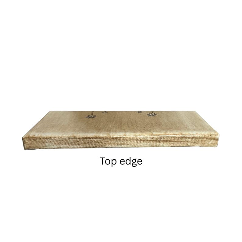Op de afbeelding: Een rechthoekig canvaspaneel met een getextureerd beige oppervlak. De bovenrand is voorzien van twee kleine, donkere, stervormige illustraties die uit elkaar staan. Het canvas is op een houten frame gespannen met een zichtbare weving.