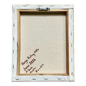 Op de afbeelding: De achterkant van een rechthoekig canvas op een houten frame met een metalen zaagtandhanger. Handgeschreven tekst in bruine inkt luidt: Beige Rolling Hills, June 2026, H. Towle, Acrylic, 20,32 cm breed bij 25,4 cm hoog.