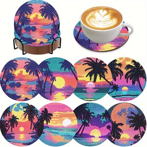 May include: A set of round drink coasters featuring diamond art designs of tropical sunset scenes with palm trees, suns, and ocean waves in vibrant pink, purple, yellow, and blue colors. The set includes a black metal holder for storage.
