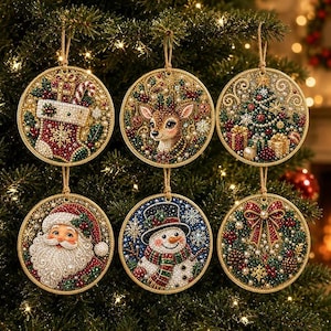 Peut inclure: Six décorations de Noël circulaires ornées de motifs en strass. Les ornements représentent une chaussette avec un sucre d'orge, un renne, un sapin décoré avec des cadeaux, le Père Noël, un bonhomme de neige et une couronne avec un nœud rouge.