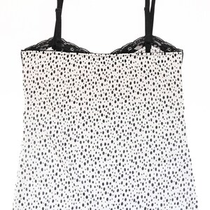 May include: White tank top with black polka dots and black lace trim.