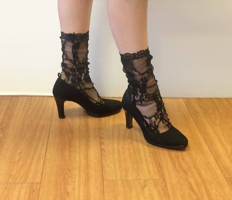 May include: A pair of black lace socks with black heels. The heels have a pointed toe and a high heel.