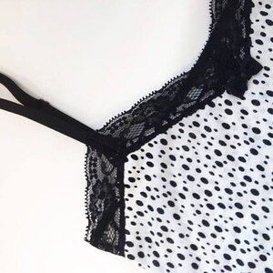 May include: Black lace trim on a white top with a black polka dot pattern.