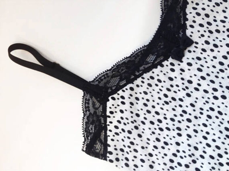 May include: Black lace trim on a white top with a black polka dot pattern.