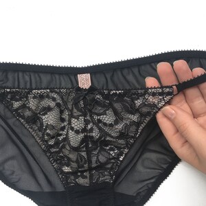 K&ouml;nnte beinhalten: Schwarze Spitzenunterw&auml;sche mit einem durchsichtigen Netzstoff und einem rosa "Victoria's Secret"-Etikett.