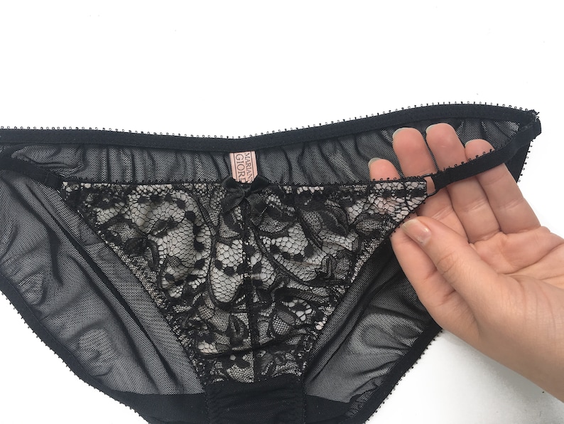 K&ouml;nnte beinhalten: Schwarze Spitzenunterw&auml;sche mit einem durchsichtigen Netzstoff und einem rosa "Victoria's Secret"-Etikett.