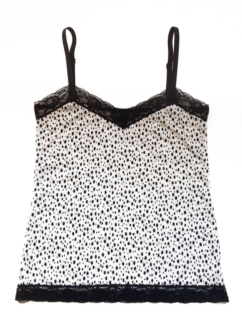 May include: A white tank top with black polka dots and black lace trim.