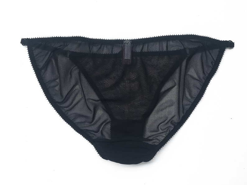 K&ouml;nnte beinhalten: Schwarze, durchsichtige Spitzenunterw&auml;sche mit zartem Besatz. Die Unterw&auml;sche hat ein schlichtes Design und ist aus einem weichen, bequemen Material gefertigt.