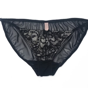 K&ouml;nnte beinhalten: Schwarze Spitzenunterw&auml;sche mit einem durchsichtigen Netzstoff. Die Unterw&auml;sche hat ein zartes florales Spitzenmuster und ein kleines rosa Etikett mit der Aufschrift "Victoria's Secret".