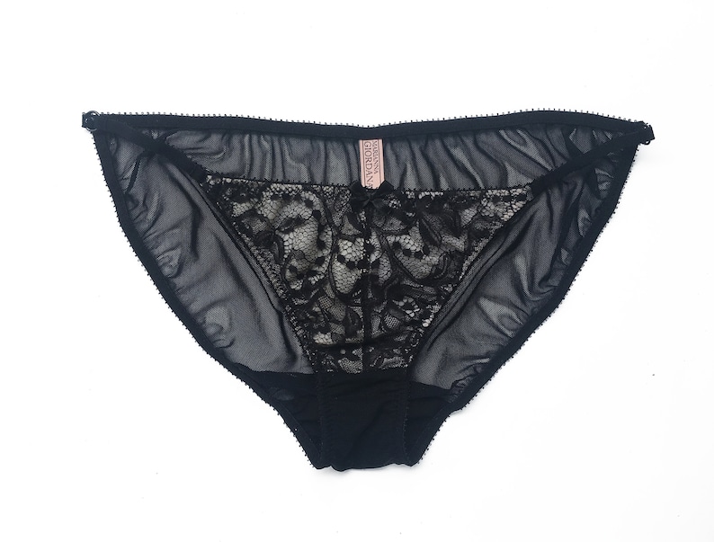 K&ouml;nnte beinhalten: Schwarze Spitzenunterw&auml;sche mit einem durchsichtigen Netzstoff. Die Unterw&auml;sche hat ein zartes florales Spitzenmuster und ein kleines rosa Etikett mit der Aufschrift "Victoria's Secret".