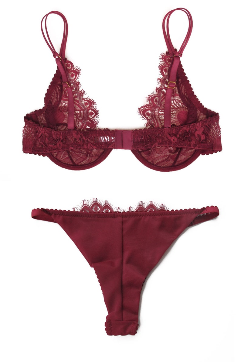 Puede incluir: Un conjunto de lencer&iacute;a de encaje color burdeos con un sujetador y una tanga a juego. El sujetador tiene tirantes ajustables y un cierre de gancho y ojo en la espalda. La tanga tiene una cintura baja y un borde de encaje.