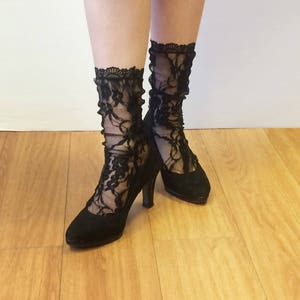 May include: A pair of black lace socks with floral patterns worn with black heels.