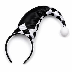 Puede incluir: Una diadema negra con un accesorio de sombrero curvo y puntiagudo. El sombrero est&aacute; hecho de una tela satinada con un patr&oacute;n de cuadros de diamantes en blanco y negro y termina con un peque&ntilde;o pomp&oacute;n blanco y redondo en la punta.