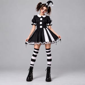 Puede incluir: Un disfraz de buf&oacute;n en blanco y negro que consiste en un vestido de manga corta con cuello blanco, tres botones blancos grandes y un dobladillo con volantes. El conjunto incluye un gorro de buf&oacute;n a juego con pompones, medias a rayas y botas.