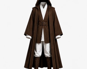 Puede incluir: Una túnica marrón con capucha de cuerpo entero sobre una túnica blanca y pantalones blancos. El conjunto incluye un cinturón marrón con hebilla en la cintura y botas de color marrón oscuro. El traje presenta mangas anchas y una capucha.