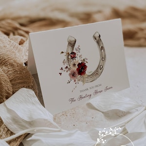 May include: A folded card with a horseshoe illustration and floral accents. The card reads "THANK YOU FROM The Healing Horse Farm" in a burgundy script. The Ann Green Card Company logo is in the lower right corner.