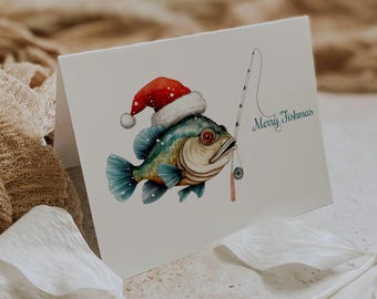 May include: A white greeting card featuring a colorful illustration of a fish wearing a red and white Santa hat. The fish is holding a fishing rod, and the text Merry Fishmas is printed in green script to the right of the fish.