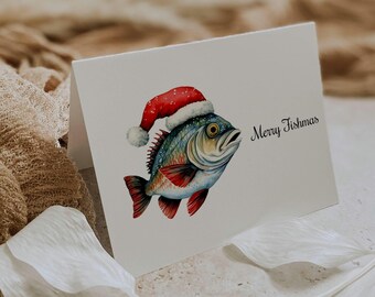 May include: A white greeting card featuring a watercolor illustration of a fish wearing a red and white Santa hat. The fish has blue, green, and red scales. The text Merry Fishmas is printed in black script on the right side of the card.