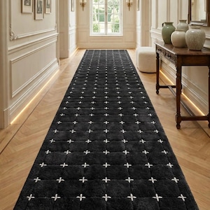Könnte beinhalten: Ein langer, rechteckiger schwarzer Läufer mit einem Gittermuster aus weißen Kreuzstichdetails. Der Teppich hat einen dicken, strukturierten Flor und liegt mittig auf einem hellen Holzboden. Der Text UNIQUE RUGS DECOR ist zu sehen.