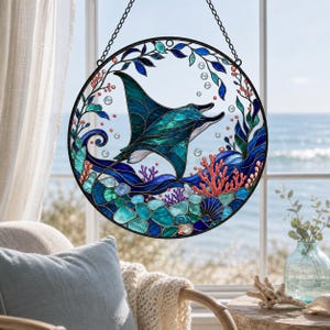 May include: A circular stained glass suncatcher featuring a teal and blue manta ray swimming among coral reefs, seaweed, and bubbles. The design is enclosed in a black metal frame and suspended by a chain, showcasing vibrant aquatic colours.
