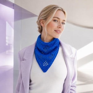 May include: A vibrant royal blue triangular knit scarf featuring a delicate openwork diamond pattern throughout the fabric. The scarf is styled as a neckerchief, resting against a white top and a light lavender blazer, showcasing its texture.