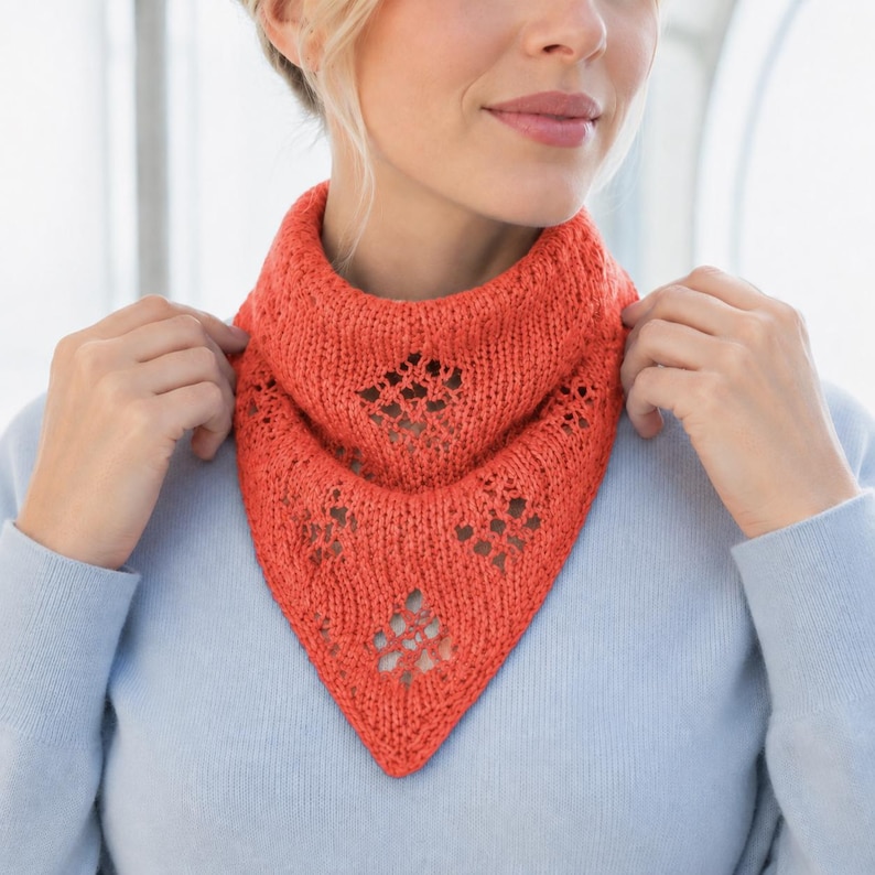 May include: A bright coral orange knitted neckerchief featuring a triangular shape and a delicate lace-like diamond pattern. The accessory is crafted with a textured yarn and sits around the neck, showcasing an openwork design throughout the fabric.