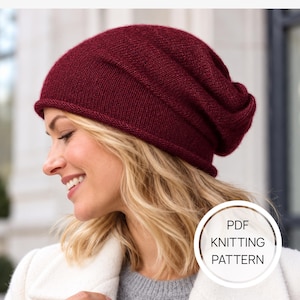 Può includere: Un berretto in maglia color bordeaux intenso con bordo arrotolato e vestibilità morbida. L'immagine presenta una sovrapposizione grafica circolare bianca con il testo PDF KNITTING PATTERN in nero, indicando un documento digitale.