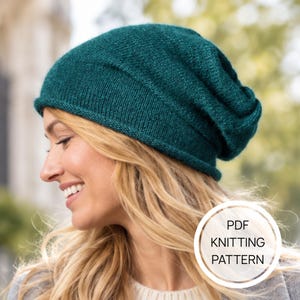 May include: A dark teal knitted beanie with a rolled brim and a slouchy fit. The image includes a white circular graphic with the text PDF KNITTING PATTERN printed in black, indicating this is a digital document for creating the headwear.