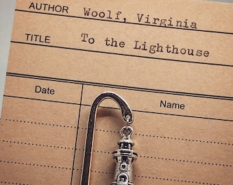 May include: A silver bookmark with a lighthouse charm. The bookmark is on a brown card with the text "AUTHOR Woolf, Virginia" and "TITLE To the Lighthouse".