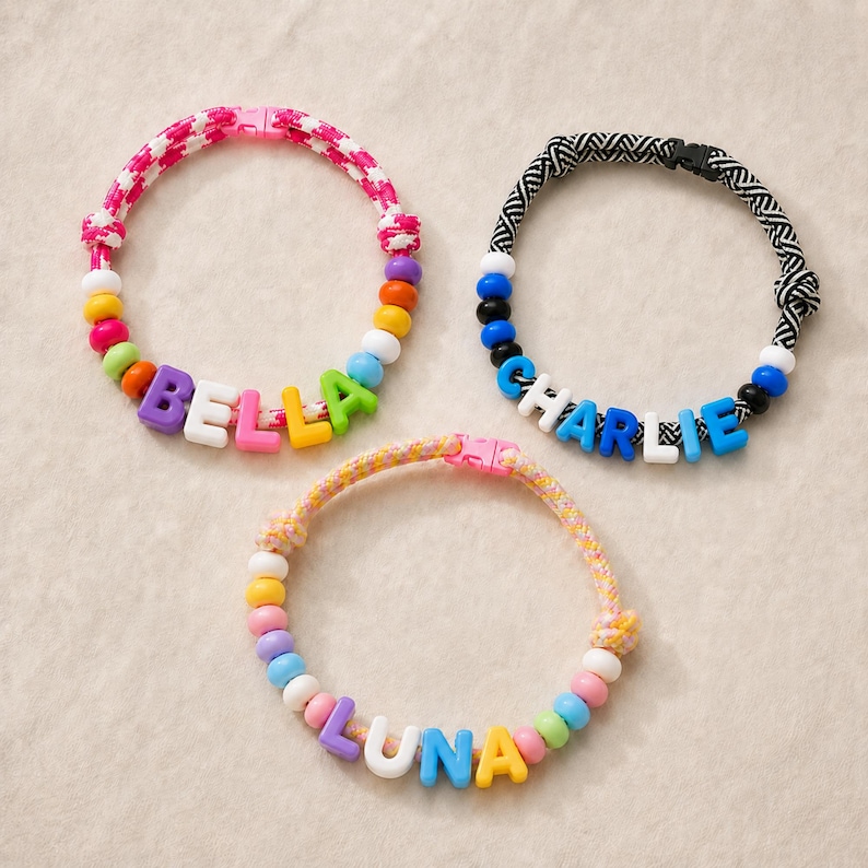 May include: Three circular collars featuring woven fabric bands and colorful plastic beads. One collar has a pink and white houndstooth pattern with the name BELLA, one has a black and white chevron pattern with CHARLIE, and one has a yellow and pink weave with LUNA.