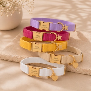 May include: A stack of five pet collars in lavender, magenta, yellow, beige, and white. Each collar features a gold-tone metal buckle engraved with a name and phone number, a matching D-ring, and a dangling gold-tone star or heart-shaped charm.