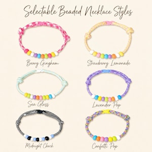 May include: Six beaded necklaces labeled Selectable Beaded Necklace Styles. The styles are Berry Gingham, Strawberry Lemonade, Sea Glass, Lavender Pop, Midnight Check, and Confetti Pop. Each necklace features a cord with beads and a plastic clasp.