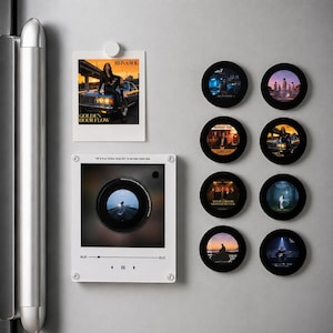 Puede incluir: Una colección de decoraciones magnéticas con temática musical que incluye un marco cuadrado blanco con un recorte circular central, un marco rectangular blanco con la foto de una persona sobre un coche y ocho imanes negros circulares con portadas.