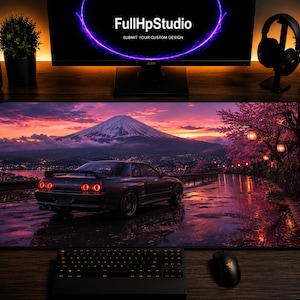 May include: A rectangular desk mat featuring a printed landscape of a dark sports car parked on a wet road at sunset, with Mount Fuji in the background, cherry blossom trees, and hanging lanterns. The scene is rendered in shades of purple and pink.