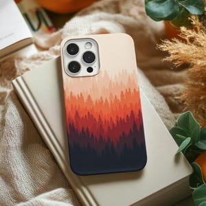May include: A smartphone case featuring a gradient forest print that transitions from a light cream color at the top to a deep dark navy blue at the bottom, with layers of pine tree silhouettes in shades of orange, red, and dark maroon in between.
