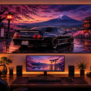 May include: A large wall-mounted display showing a black Nissan 300ZX parked on a wet road with Mount Fuji, cherry blossoms, and a pagoda in the background. Below, a computer monitor displays a torii gate over water at sunset on a desk.