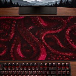 May include: A rectangular desk mat featuring a dark black background with a vibrant magenta and deep red octopus tentacle pattern. The design displays multiple winding tentacles with visible suction cups covering the entire surface area.