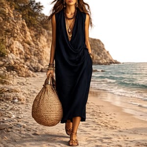 May include: A sleeveless navy blue midi dress with a deep cowl neckline and draped fabric detail at the waist. The garment is paired with a large, round, woven straw handbag, layered gold necklaces, and brown strappy sandals.