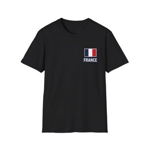 May include: A black short-sleeve t-shirt featuring a small rectangular French flag graphic on the upper left chest area. Below the flag, the word FRANCE is printed in a clean, white, sans-serif capital font, centered against the black fabric.