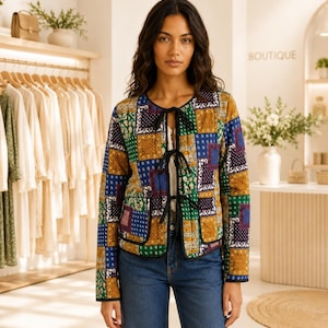 Puede incluir: Una chaqueta acolchada de manga larga con un patrón de patchwork multicolor en tonos azul, verde, amarillo y morado. La chaqueta tiene un cuello redondo, ribetes negros en los bordes y tres lazos de cinta negra para el cierre frontal.