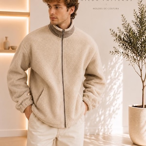 Puede incluir: Una chaqueta de forro polar beige con cremallera, cuello alto y ribete de cremallera gris oscuro. La chaqueta tiene mangas largas con puños elásticos y dos bolsillos laterales. El texto HP HILDA PATTERNS MOLDES DE COSTURA es visible arriba.